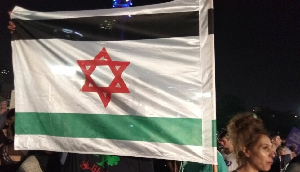 Et flagg kombinerer elementer fra det israelske og det palestinske flagget under en demonstrasjon i Tel Aviv i 2018.