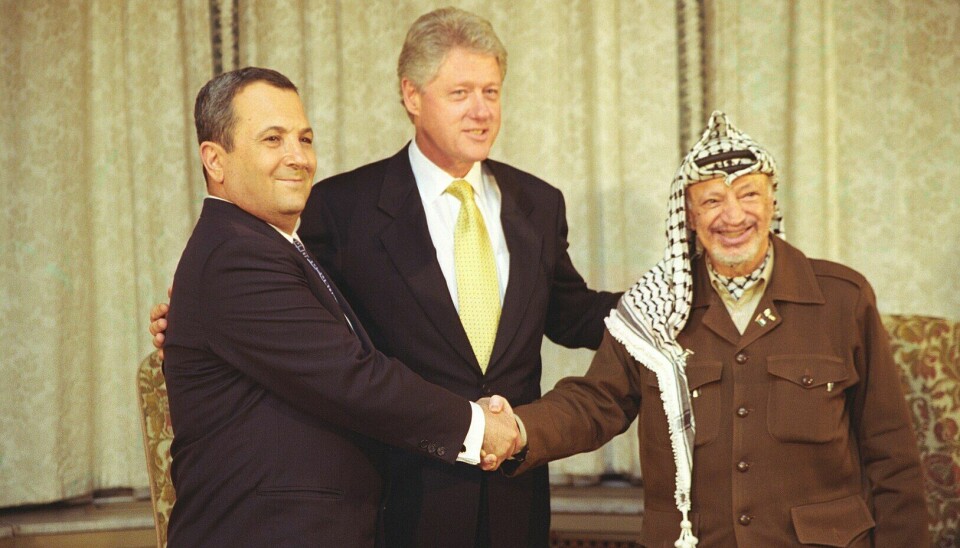 Israels statsminister Ehud Barak og palestinernes leder Yasir Arafat tar hverandre i hendene i Det hvite hus med USAs president Bill Clinton i 2000.