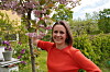 Nina Brochmann i rød genser står ved et blomstrende tre i en frodig hage.