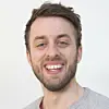 Portrett av Ole Fredrik Norbye, smilende mot kamera foran en lys bakgrunn.
