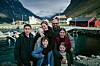 Familien fra filmen Fjord ved en fjord, med båter, hus og fjell i bakgrunnen.