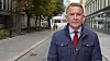 Andreas Kravik, i mørk jakke og rødt slips står i Akersgata ved Stortinget